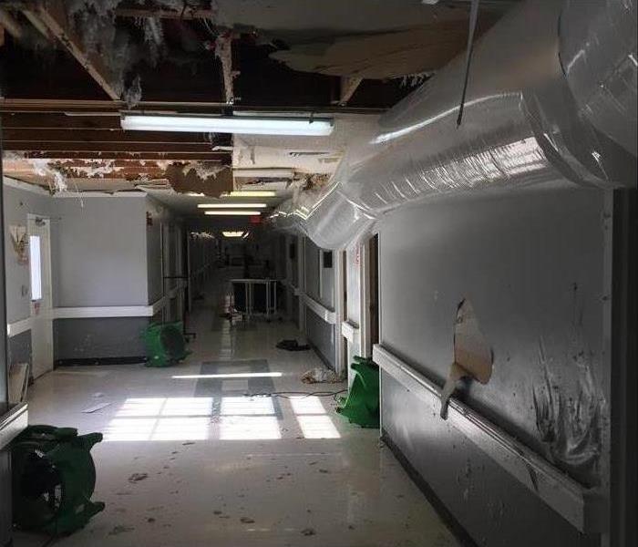 dehumidifier running along wall in a medical facility, exposed water damaged ceiling, air mover on the floor, Memphis, TN