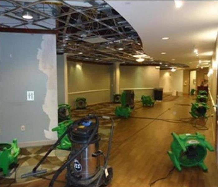 green air movers drying out hardwood floor in a commercial building