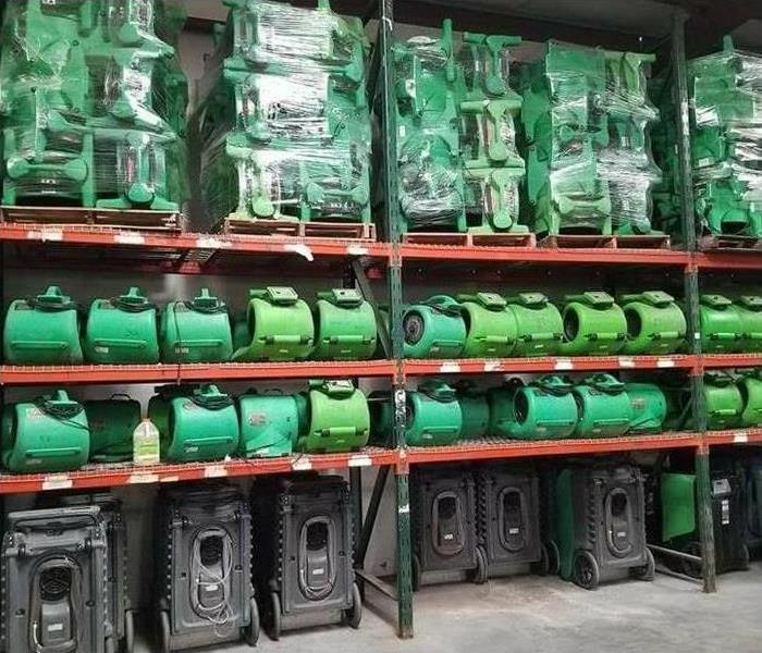 racks of air movers and hepa filters, SERVPRO green, all in order in a warehouse