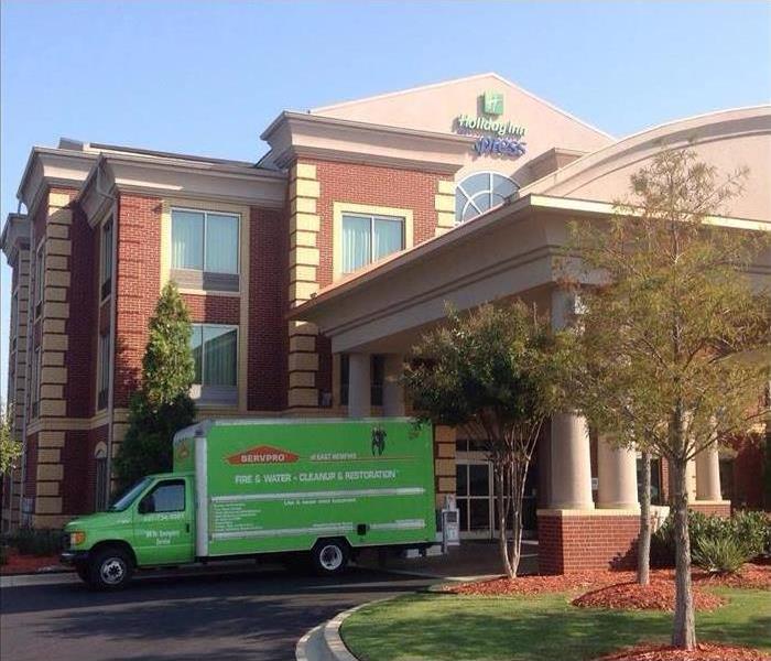 Holiday Inn Express brick building entrance with a green SERVPRO box truck out front, blue sky
