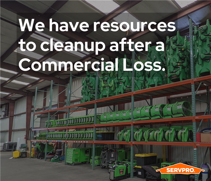 a storage rack full of air movers along a wall, going up the side of an industrial warehouse, SERVPRO green